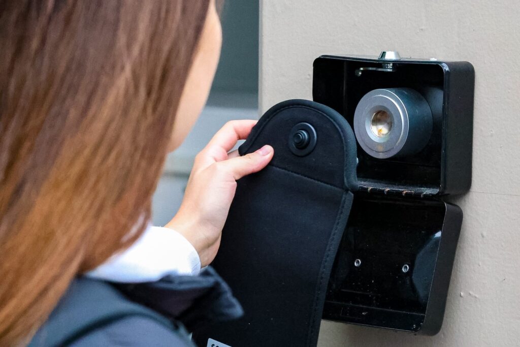 Alumna desbloqueando su bolsa de celular KIKU en la estación de la escuela a la salida